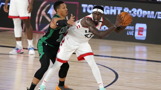 Pascal Siakam tient un adversaire à distance lors d'un match contre les Celtics de Boston.