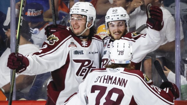 Trois joueurs de hockey d'une même équipe se sautent dans les bras.