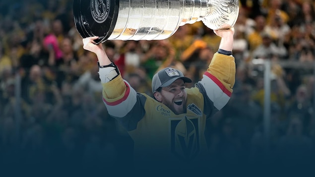 Un joueur de hockey souriant soulève à bout de bras un trophée