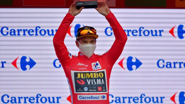 Le cycliste prend la pose en soulevant le trophée du jour.