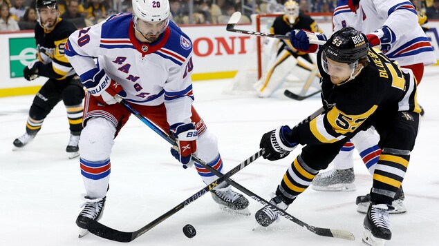 Chris Kreider and Teddy Blueger fight for the puck. 