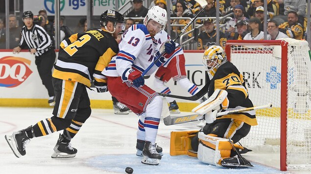 Alexis Lafrenière launches towards the puck in front of Louis Domingue. 