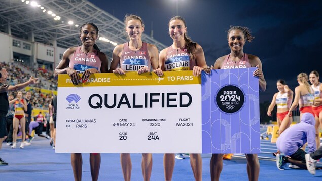 Quatre coureuses tiennent une affiche sur laquelle il est écrit : Qualified (qualifiées).