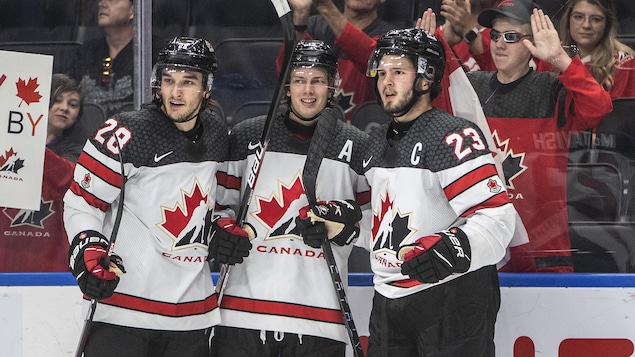 Trois hockeyeurs canadiens célèbrent un but.