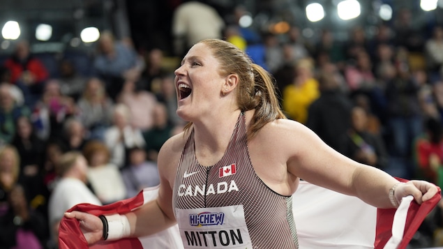 Sarah Mitton crie de joie, le drapeau canadien dans les mains, après sa victoire lors des championnats du monde intérieurs d'athlétisme à Glasgow, en Écosse. 