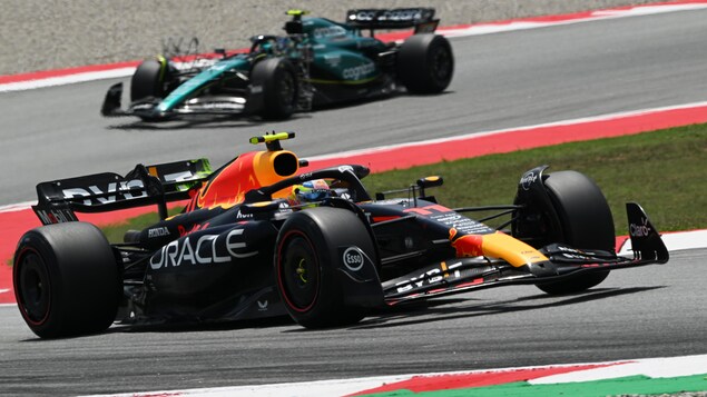 Deux monoplaces F1 roulent sur un circuit.  
