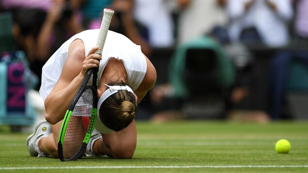 Elle est accroupie sur le gazon.
