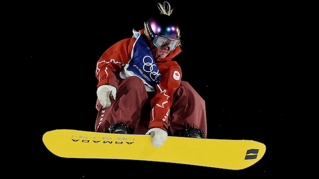 Une planchiste aggripe sa planche lors d'un saut aux Jeux olympiques.