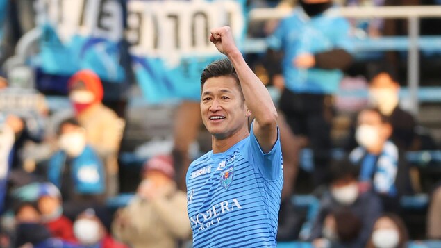 Il lève le poing gauche pendant un match de soccer.