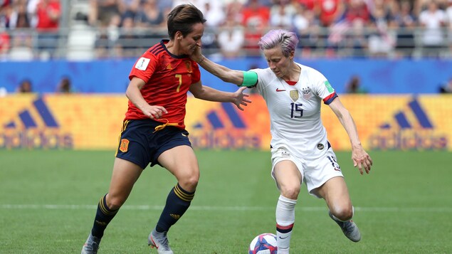 Elle porte sa main au visage d'une adversaire en tentant de maîtriser le ballon.