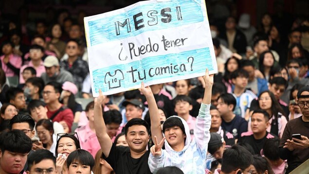 Des partisans brandissent une affiche destinée au joueur de soccer Lionel Messi.