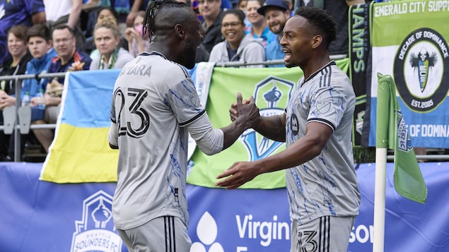 Deux joueurs de soccer se serrent la main pour célébrer.