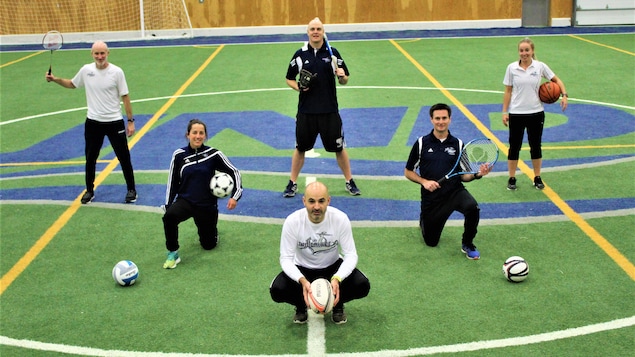 Six enseignants d'éducation physique sur un terrain couvert.