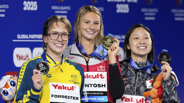 La médaillée d'or Summer McIntosh du Canada, au centre, entourée de la médaillée d'argent Jenna Forrester d'Australie, à gauche, et de la médaillée de bronze Mio Narita du Japon, pose sur le podium après la finale du 400 mètres quatre nages individuel féminin aux Championnats du monde de sports aquatiques à Singapour.