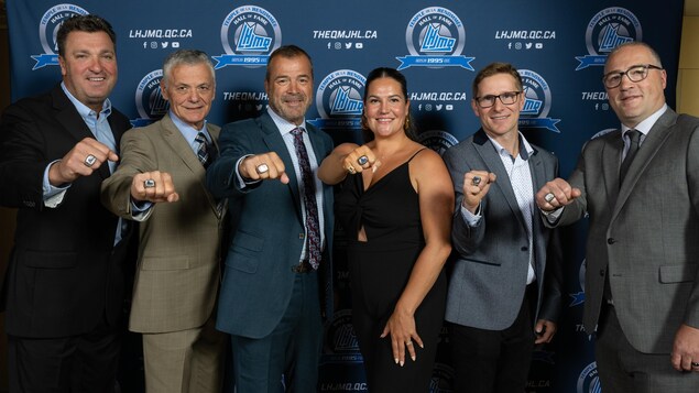 Des anciens hockeyeurs et une femme prennent la pose avec une bague.