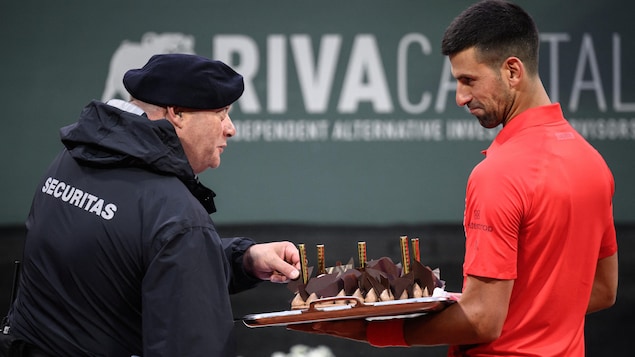 Novak Djokovic partage son gâteau d'anniversaire avec un gardien de sécurité.