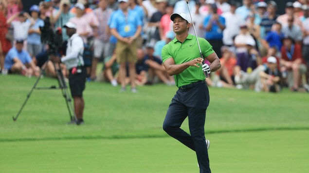 Le golfeur Tiger Woods regarde au loin et se tient sur sa jambe gauche après avoir effectué un coup.