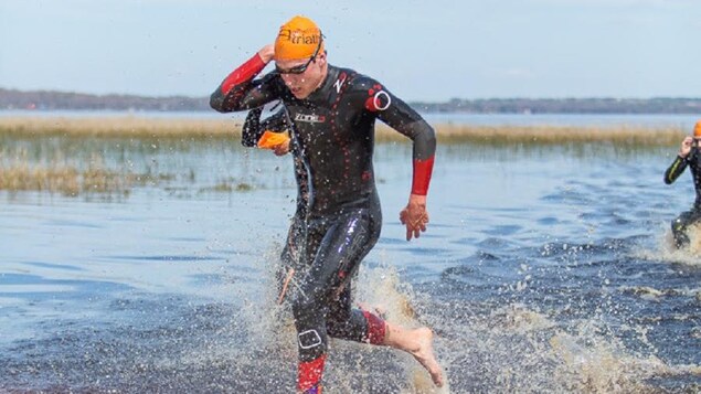 Le triathlonien en habit de nage est debout dans l'eau.