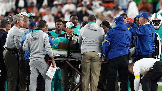 Un joueur de football est sur une civière, entouré du personnel médical de l'équipe.