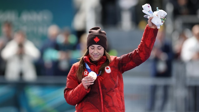 Une athlète regarde sa médaille sur le podium.