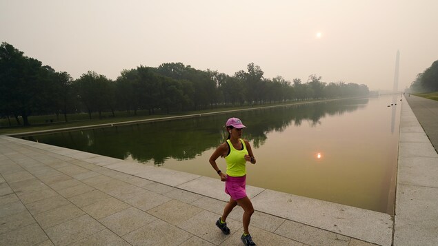 Une femme fait son jogging aux abords de la Reflecting Pool, le grand bassin devant le Monument de Washington, caché derrière une épaisse fumée qui masque même le soleil.