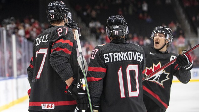Trois hockeyeurs se réunissent pour célébrer un but.