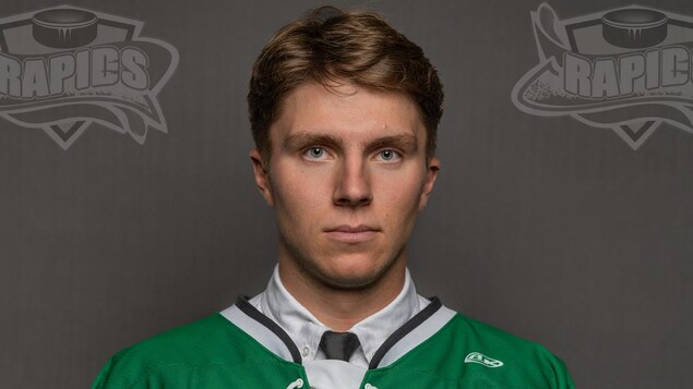 Joueur de hockey avec un chandail vert photographié devant un un fond gris