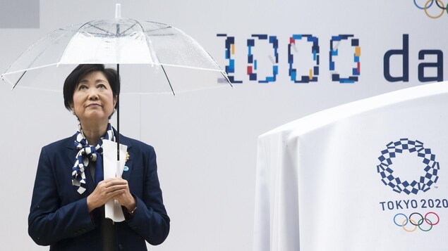 Elle tient un parapluie devant un panneau à 1000 jours des Jeux. Elle tient un parapluie devant un panneau à 1000 jours des Jeux.