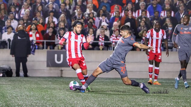 Un joueur de soccer tente de déjouer un adversaire, sans succès, pendant un match.