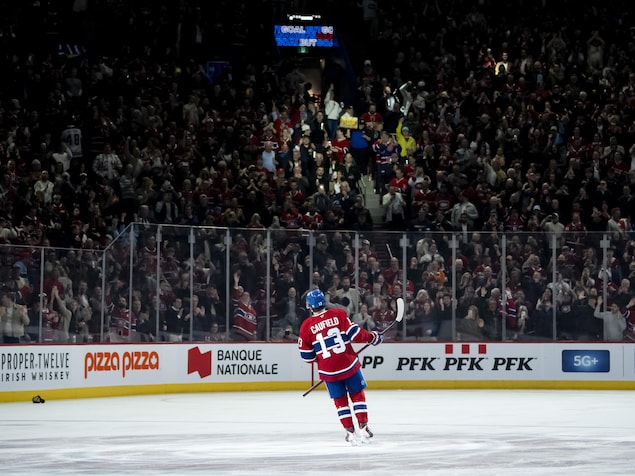 Un joueur de hockey regarde la foule qui célèbre son but. 