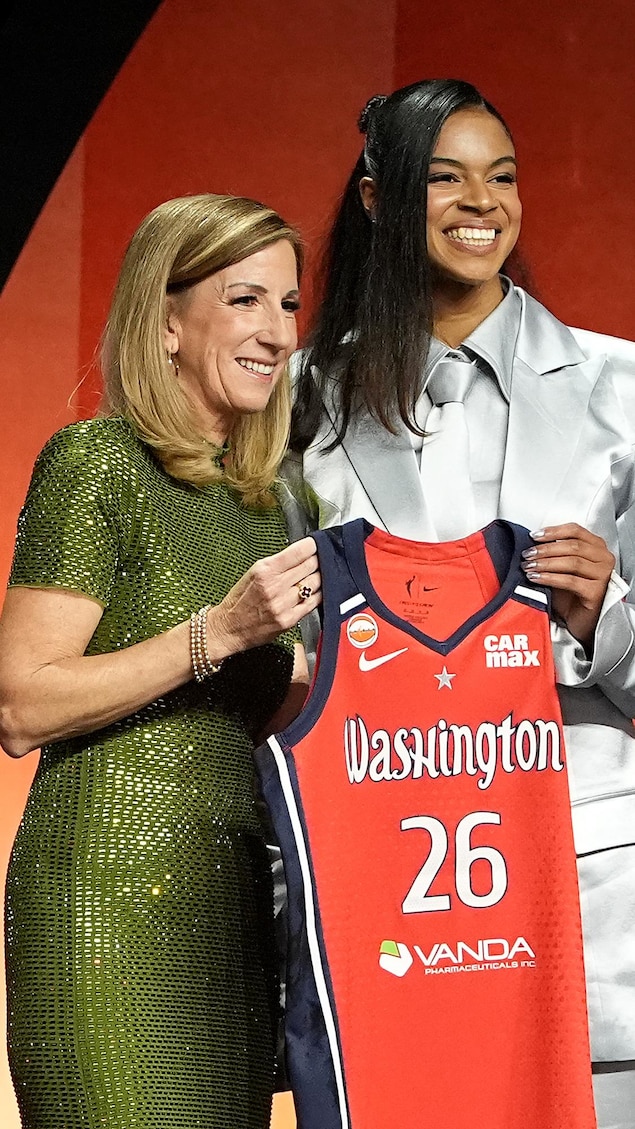 Deux femmes présentent une camisole de basketball.