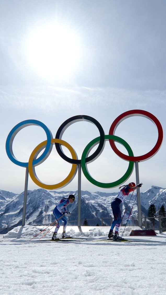 Des fondeuses skient devant les anneaux olympiques lors de l'épreuve de cross country féminin 30 km pendant les Jeux de Sotchi.