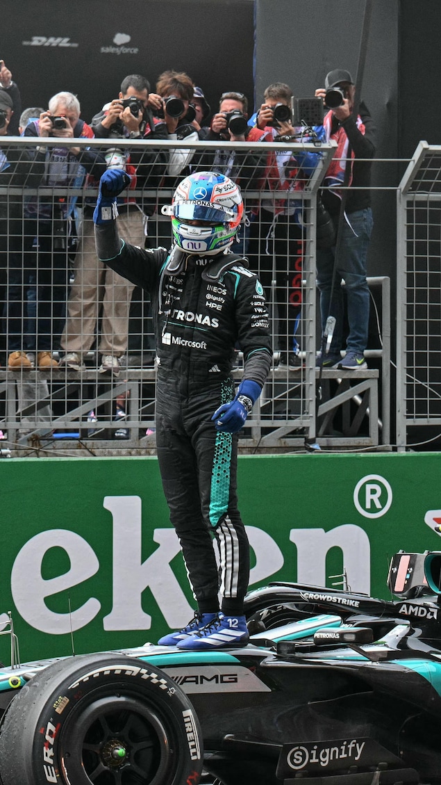 Un pilote automobile est debout sur sa monoplace de F1.
