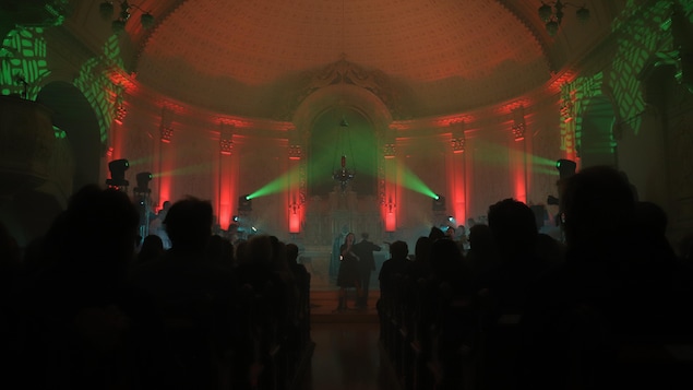 Une foule assiste à un spectacle rock dans une église.