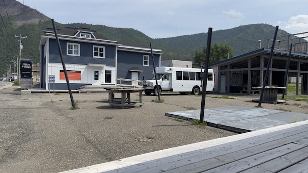 Une espace sans activité où se trouve des tables en bis, un minibus et un bâtiment fermé.