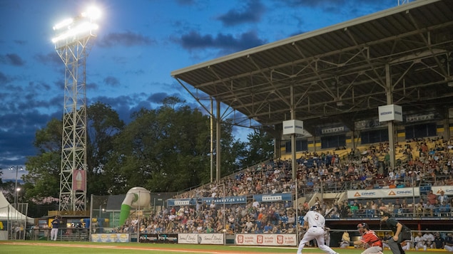 Image d'u stade de baseball avec une foule qui remplit les sièges des estrades, et des joueurs sur le terrain.