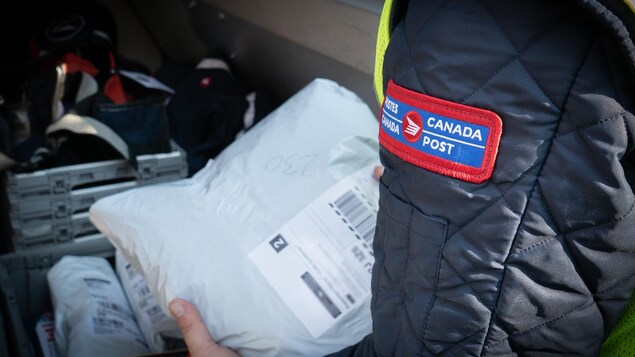 Un facteur de Postes Canada manipule un colis
