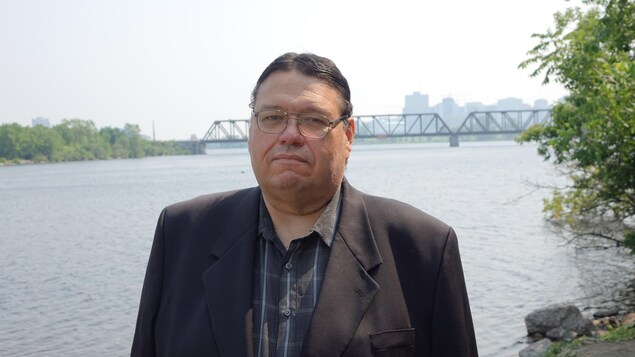 Portrait de l'homme placé devant la rivière des Outaouais et le pont Chef-William-Commanda.
