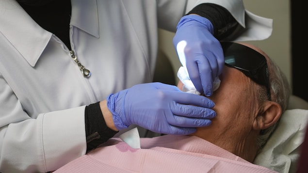Des mains gantées palpent le bouche d'un patient. 