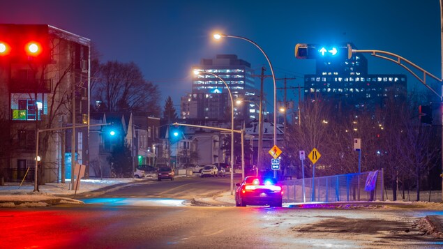 Un véhicule de police avec des gyrophares activés dans un quartier résidentiel tranquille.