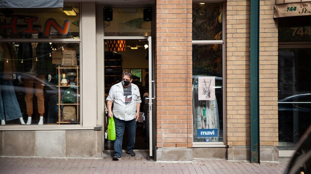 Un client sort de la boutique Séraphin, dans le Vieux-Québec, en portant son masque.