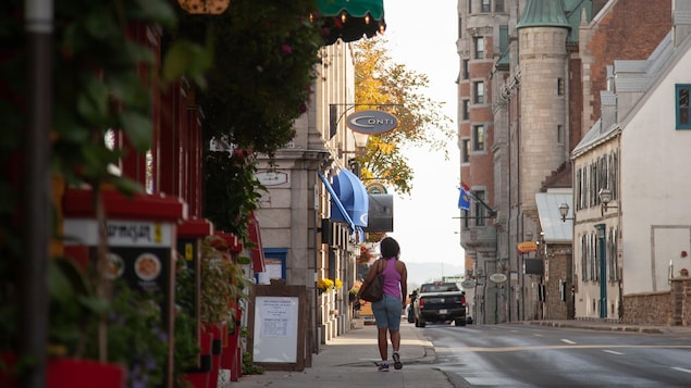 Une touriste se promène sur un trottoir vide du Vieux-Québec.