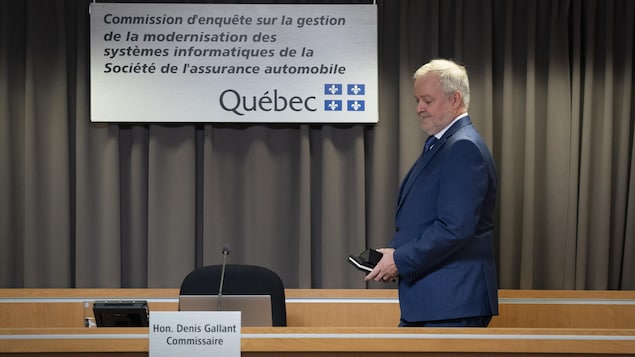 Denis Gallant marche en tenant un calepin et son téléphone cellulaire.