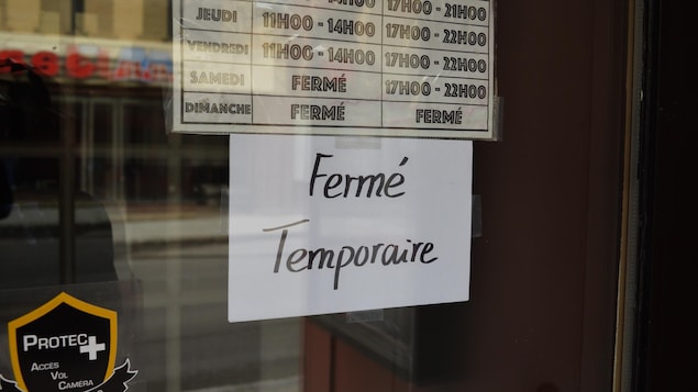 Une affiche indiquant une fermeture temporaire dans la porte d'un commerce de Québec.
