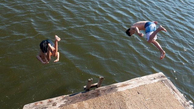 Deux adolescents sont photographiés dans les airs pendant qu'ils plongent pour se jeter dans un lac.