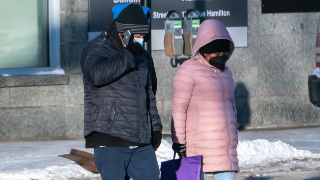 Des gens portent des masques à l'extérieur durant la pandémie de COVID-19 à Regina en hiver.