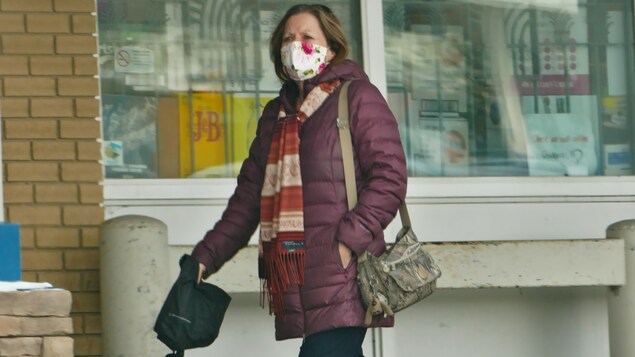 Une femme porte un masque à l'extérieur pendant la pandémie de la COVID-19 à Regina en hiver.