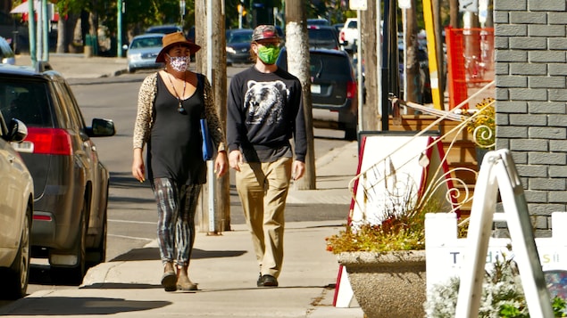 Des gens portent des masques à l'extérieur durant la pandémie de COVID-19 à Regina en automne.