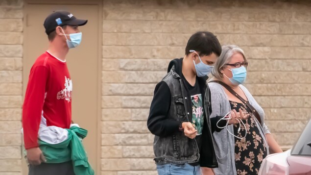 Des gens portant des masques à l'extérieur pendant la pandémie de la COVID-19 à Regina au printemps.