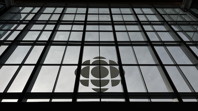 Le logo de Radio-Canada au bas d'une grande façade en verre.